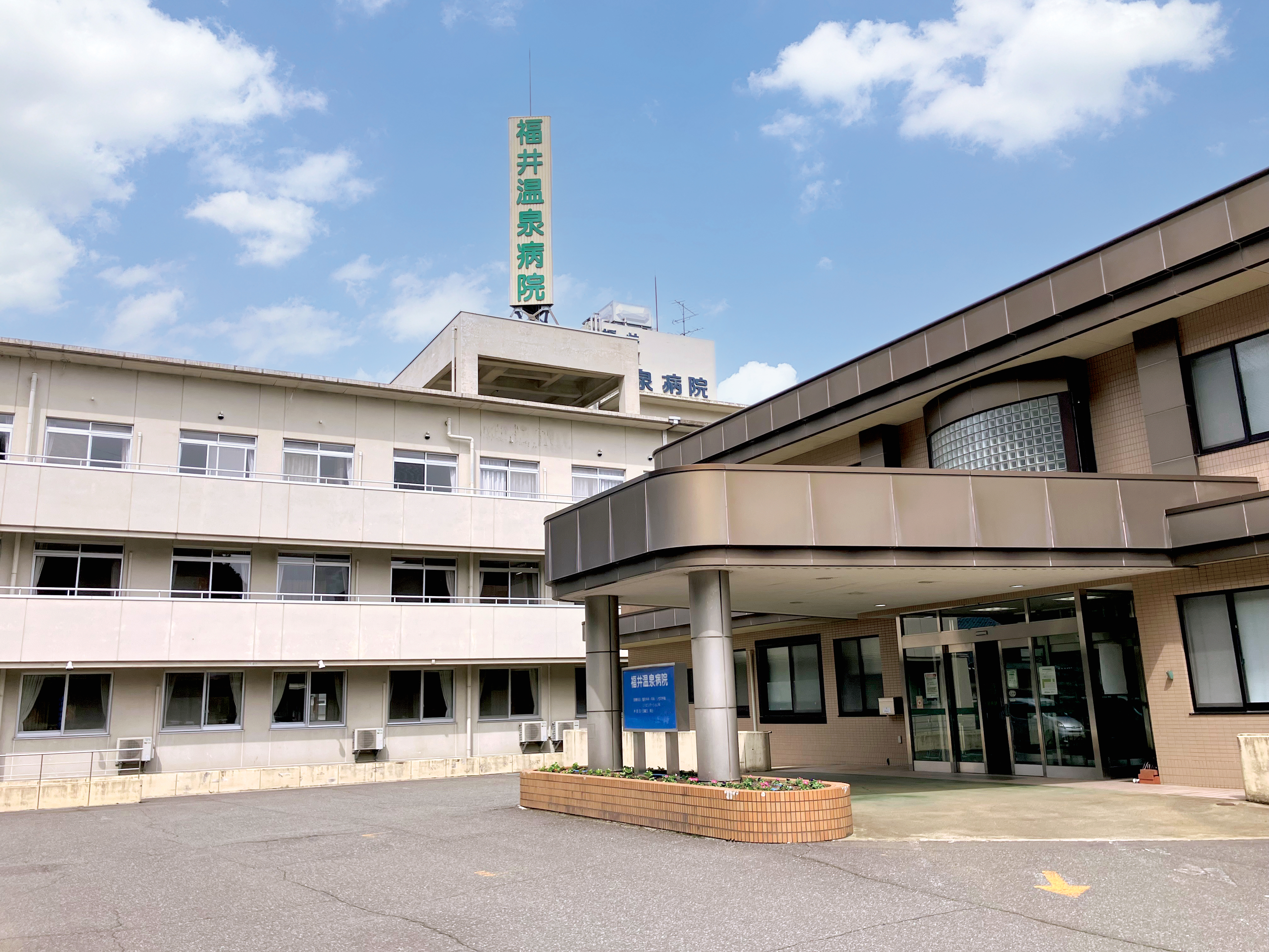 病院名の看板と正面入口が見える福井温泉病院の建物外観