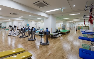 公式設備紹介に掲載された運動機器のあるリハビリテーション室