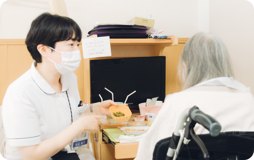 病室で食事を支えるスタッフと患者