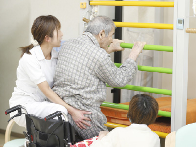 職員が利用者の立ち上がり訓練を支える場面