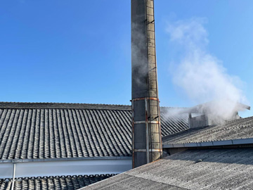 屋根と煙突から蒸気が上がる酒蔵