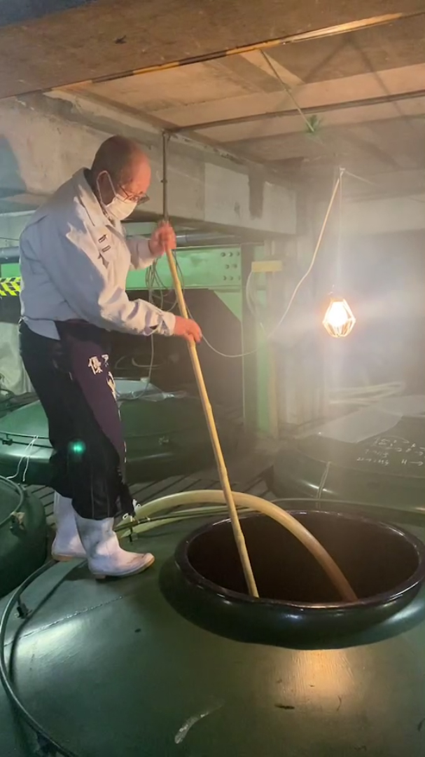 酒蔵のタンクで作業する蔵人