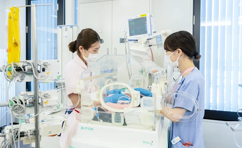 NICUで新生児をケアするスタッフと保育器