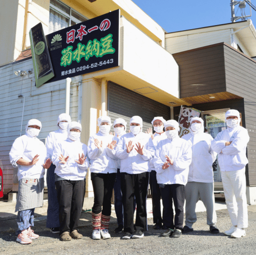 製造服のスタッフと、菊水食品の看板がある建物外観