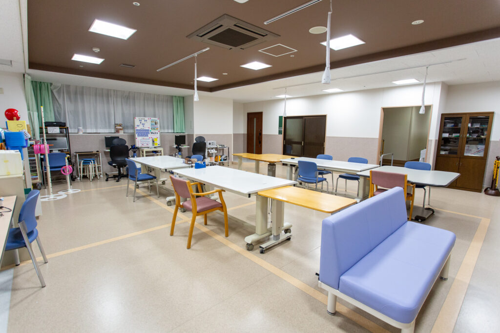 公式の中央リハビリ室案内に掲載された、訓練用テーブルと設備のある室内