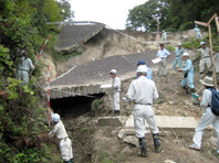 豪雨による道路損壊現場を説明する写真
