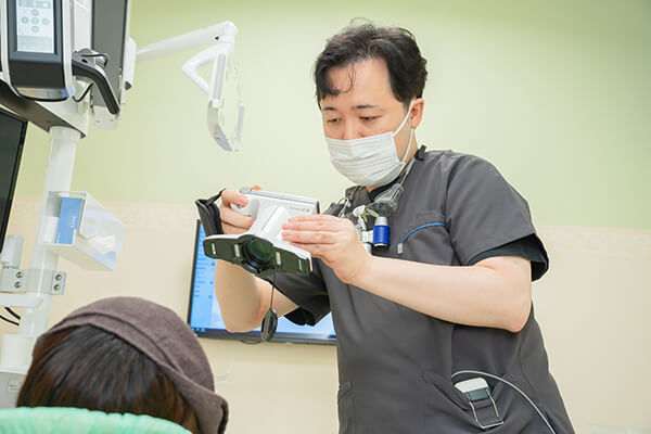 公式掲載の拡大鏡とモニターを使う歯科医師