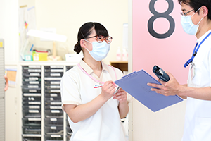 公式看護部ページに掲載された、病棟で情報共有する医療スタッフ。