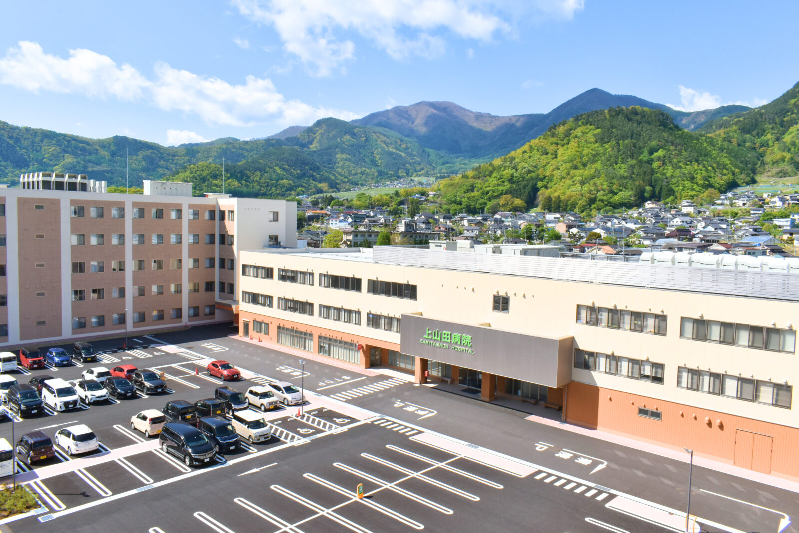 病院名が見える上山田病院の建物と周辺の山並み。