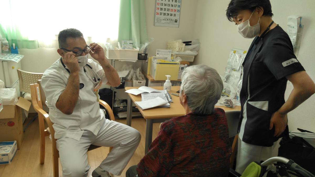 患者宅で対話する医師・看護師と患者