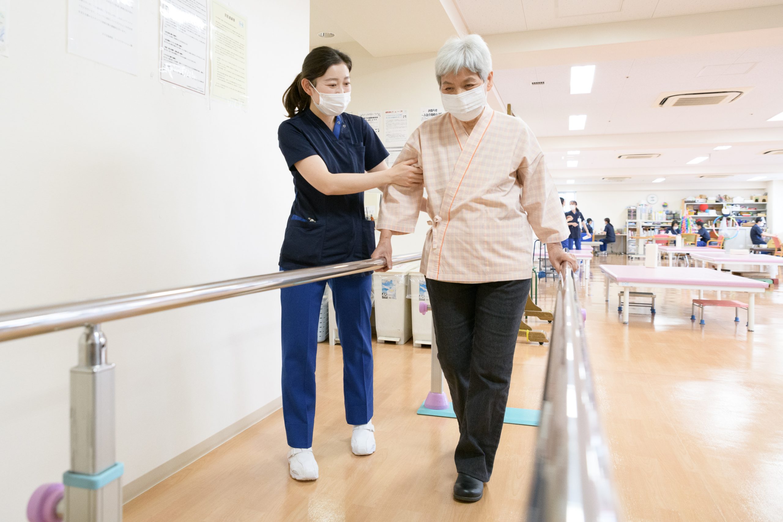 スタッフが歩行練習を支えるリハビリテーションの様子