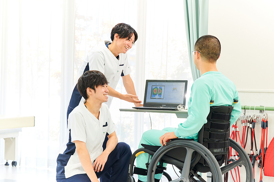 リハビリスタッフが車椅子利用者と画面を見ながら話す様子