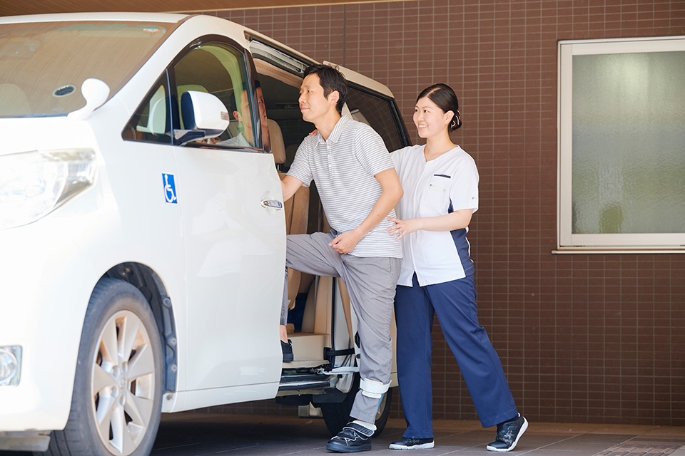 送迎車への乗車を支えるスタッフ