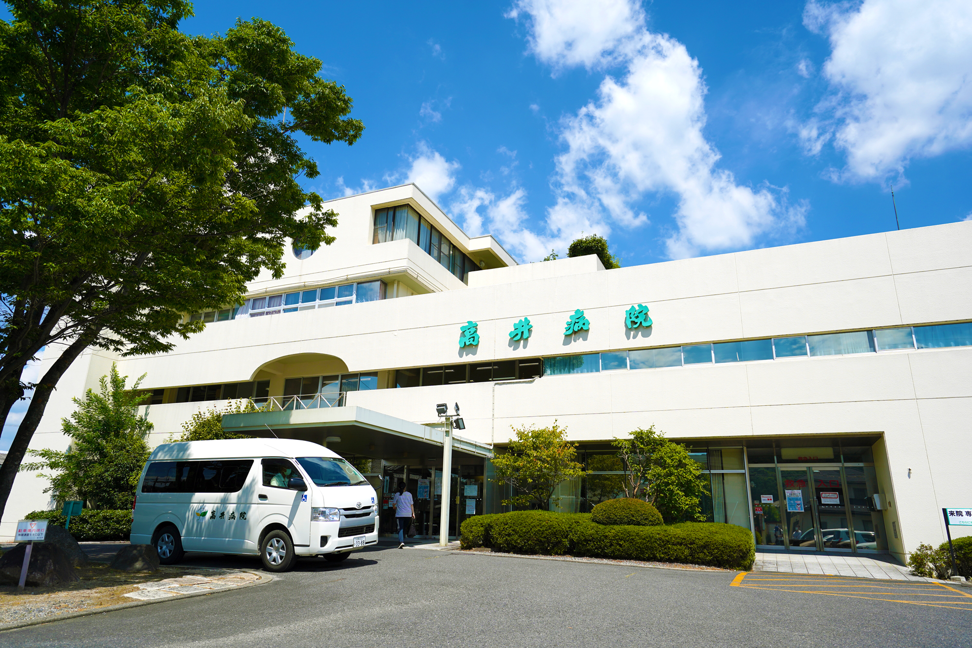高井病院の名称表示と送迎車が見える公式の建物外観
