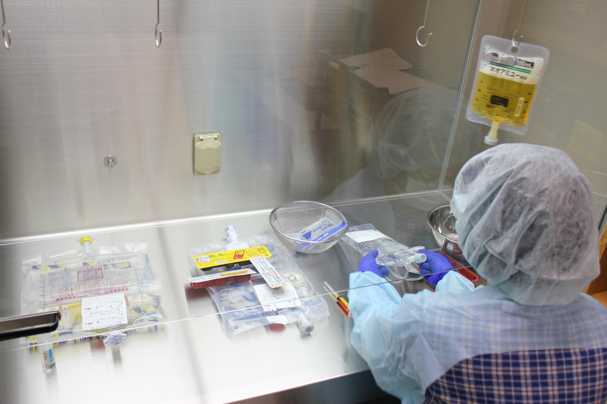 安全キャビネット内で薬剤を調製する薬剤部職員