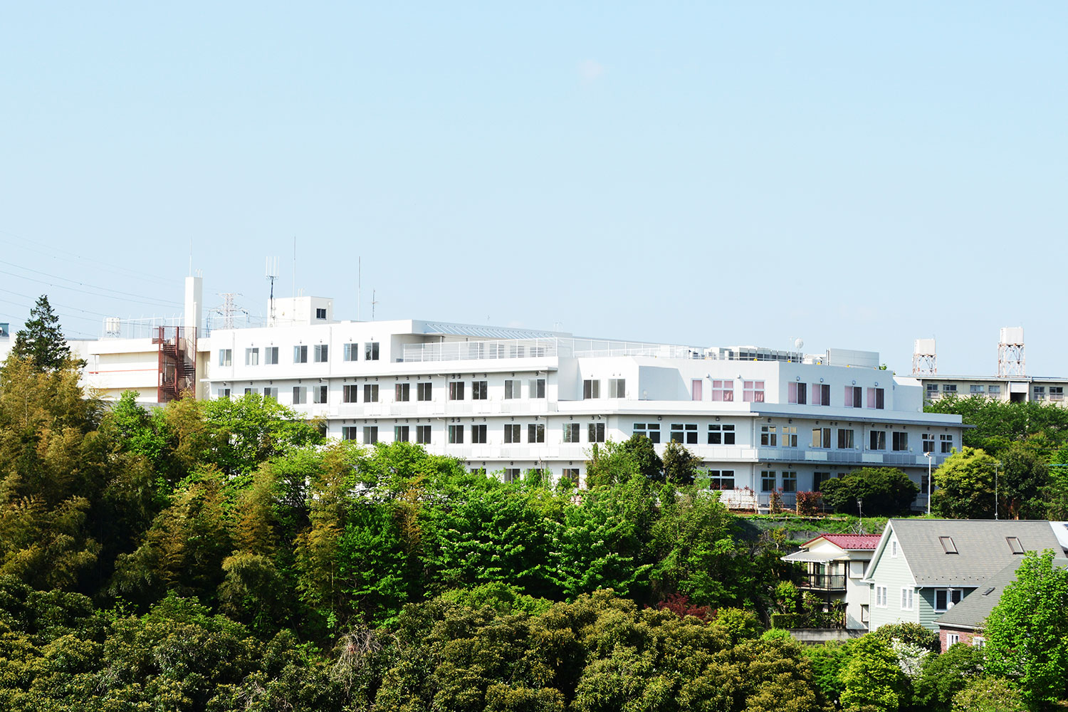緑に囲まれた保土ヶ谷病院の建物全景