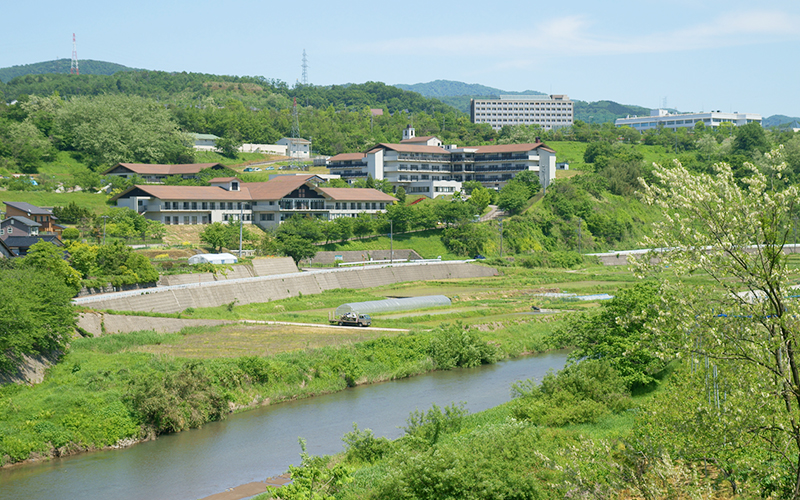 公式施設紹介に掲載される浅野川と緑に囲まれた医王ヶ丘病院の建物全景