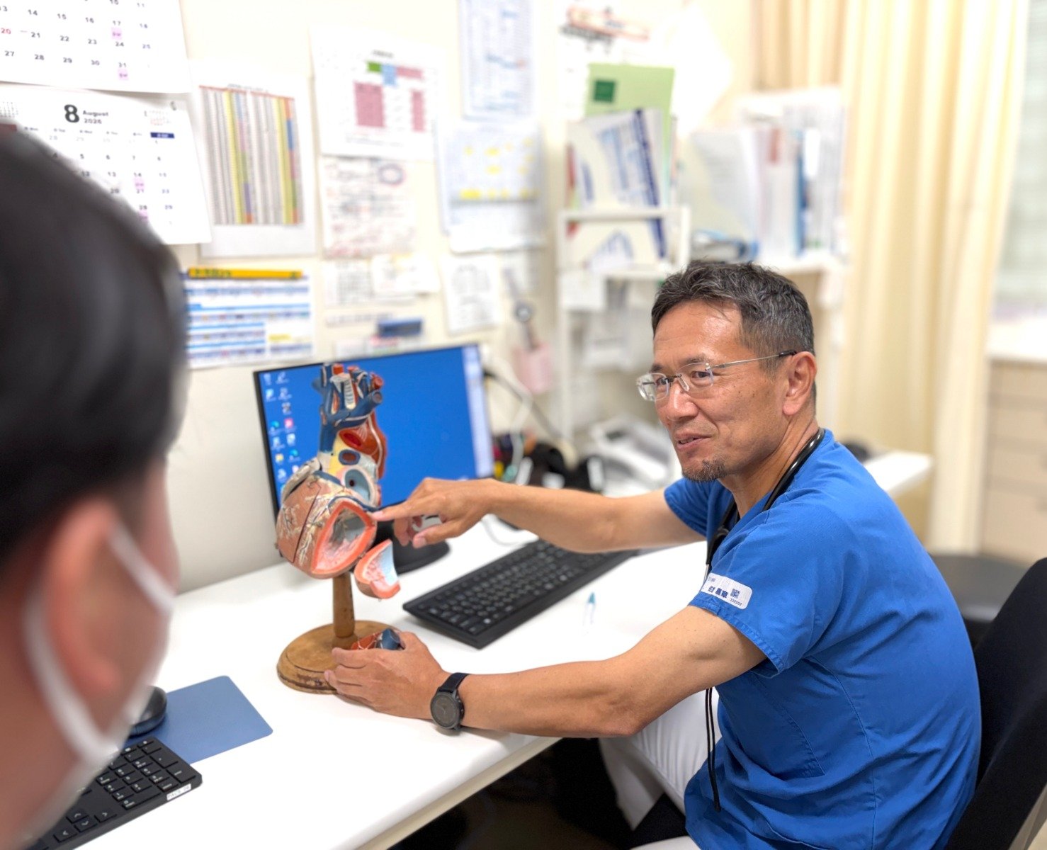 医師が診察室で心臓模型を使って説明する様子