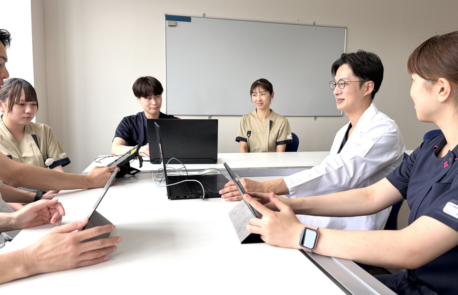 医師と職員がタブレットを囲んで話し合う様子