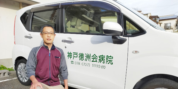神戸徳洲会病院の表示がある訪問リハビリ車両とスタッフ