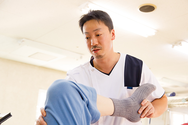 療法士が利用者の足に触れて支援する様子