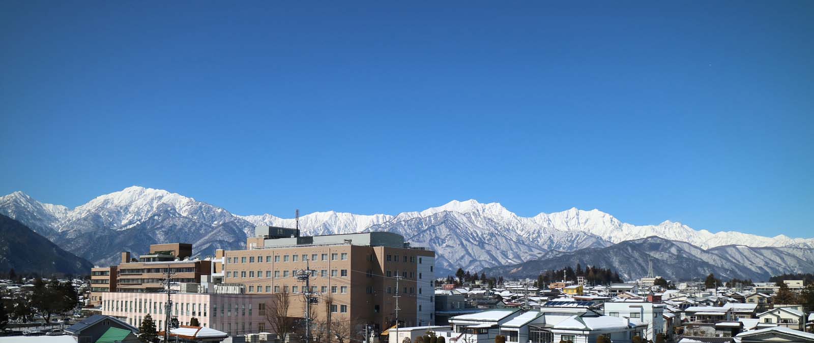 公式トップに掲出された病院外観と北アルプス