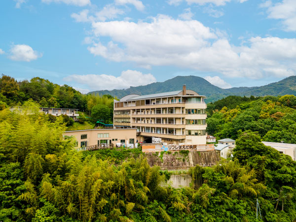 山と緑に囲まれたリフレまえだ病院の建物全景
