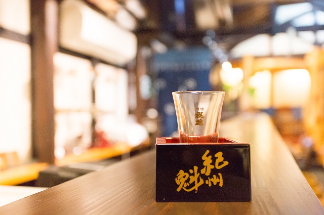 紀州魁の名が入った升と試飲用の酒器を写す公式写真
