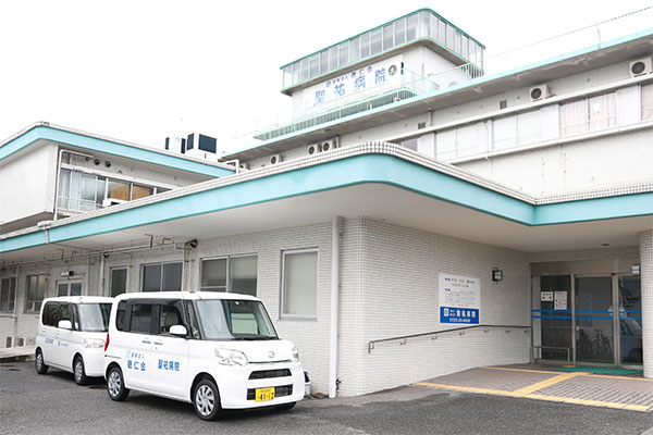 聖祐病院の名称表示が見える建物入口と外来送迎車