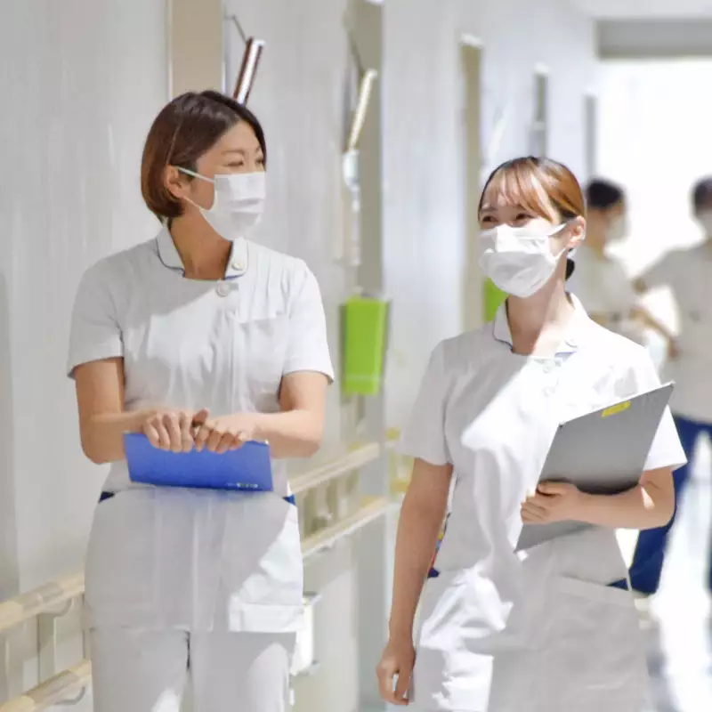 病棟の廊下で情報を確認しながら歩く看護師