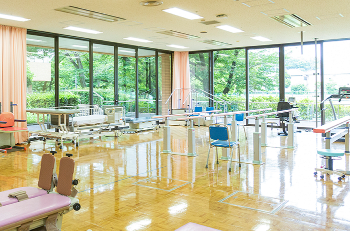公式トップに掲載される、歩行訓練設備と治療ベッドを備えた無人のリハビリテーション室