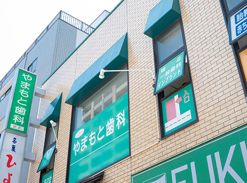 公式アクセスページに掲載された、やまもと歯科の看板と入口が見える外観