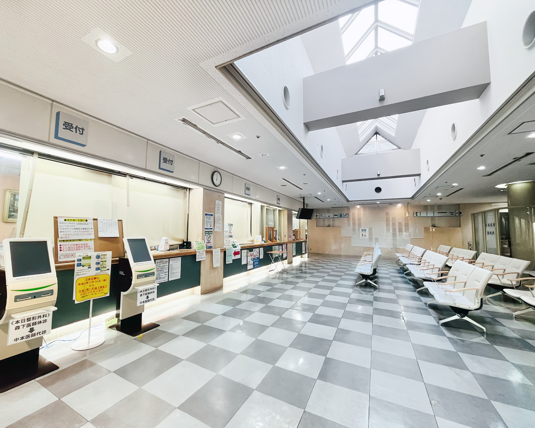 外来受付カウンターと待合椅子のある明るい院内空間